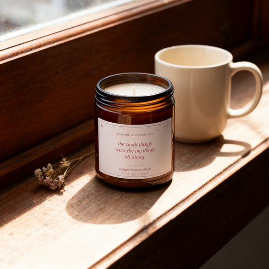 b.grateful peppered passionfruit candle on a sunlit windowsill with a ceramic mug and dried flowers