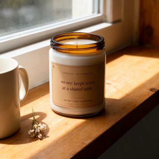 b.together coconut cream and cardamom candle on a sunlit windowsill with a ceramic mug and dried flowers